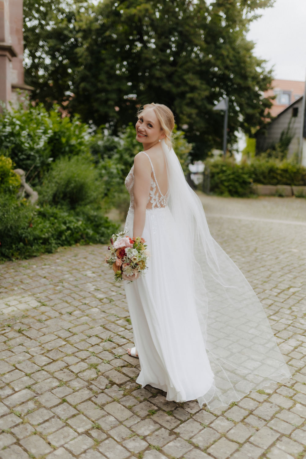 Braut dreht sich lächelnd um, Hochzeitsshooting im Grünen bei Göttingen