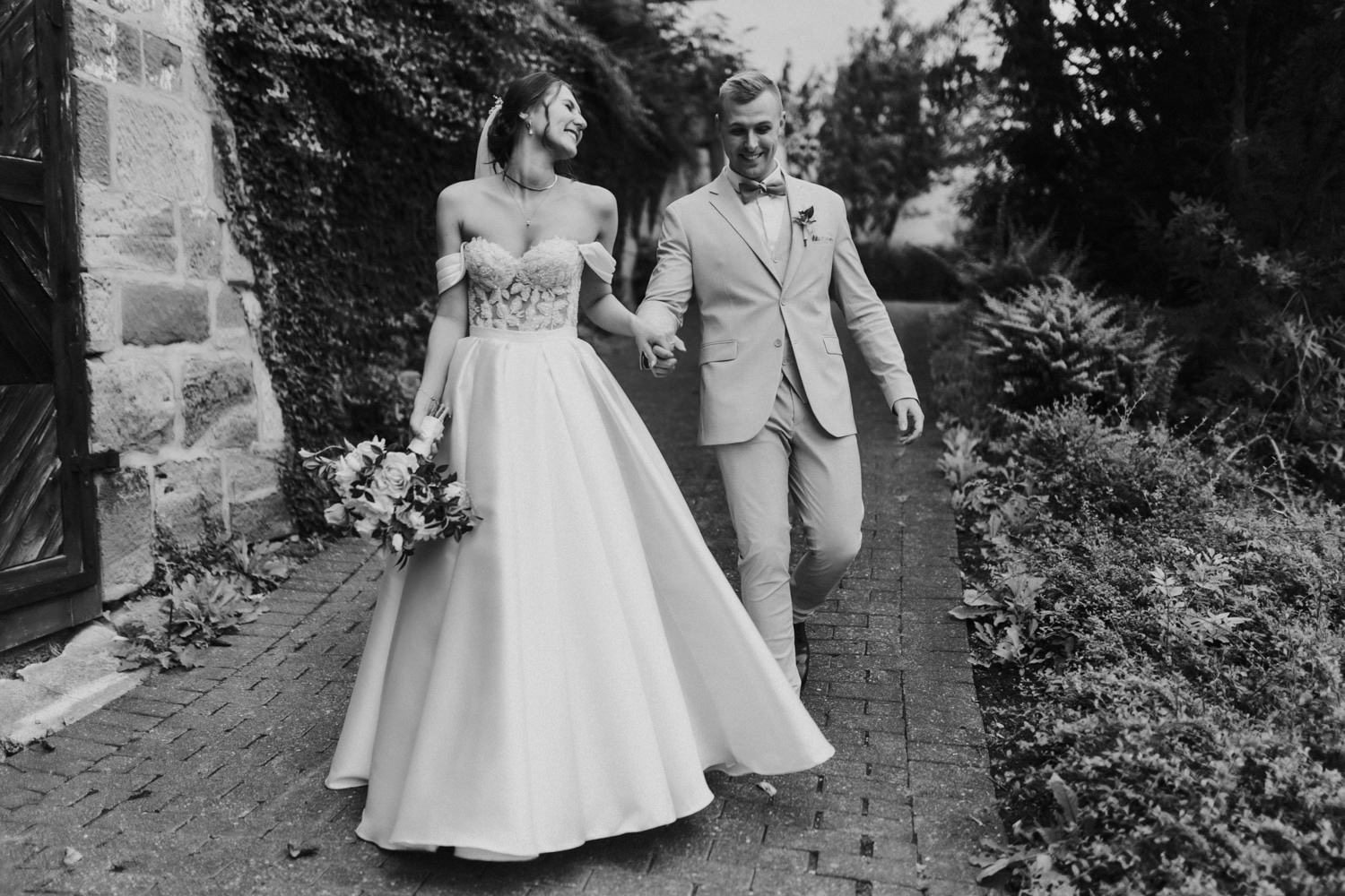 Hochzeitspaar läuft lachend durch Garten, Heiraten in Nörten-Hardenberg