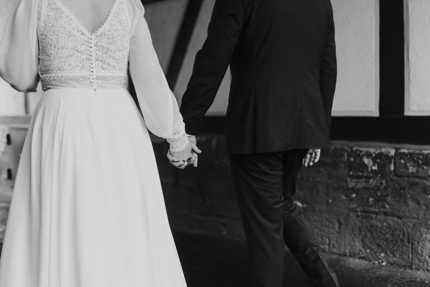 Brautpaar Hand in Hand durch Torbogen – Regenhochzeit in Kassel