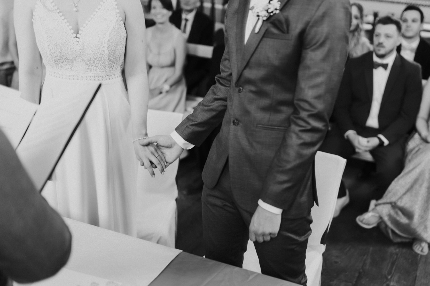 Brautpaar-haelt-sich-Hand-im-Standesamt Detailaufnahme: Braut und Bräutigam halten sich während der Trauung an den Händen