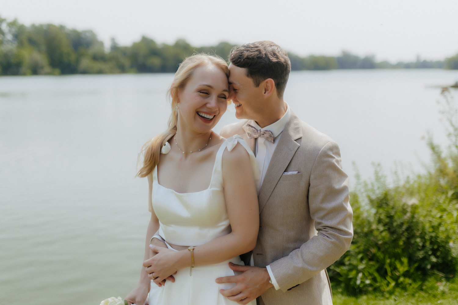 Lachendes Brautpaar am Seeufer bei sommerlicher Hochzeit in Göttingen