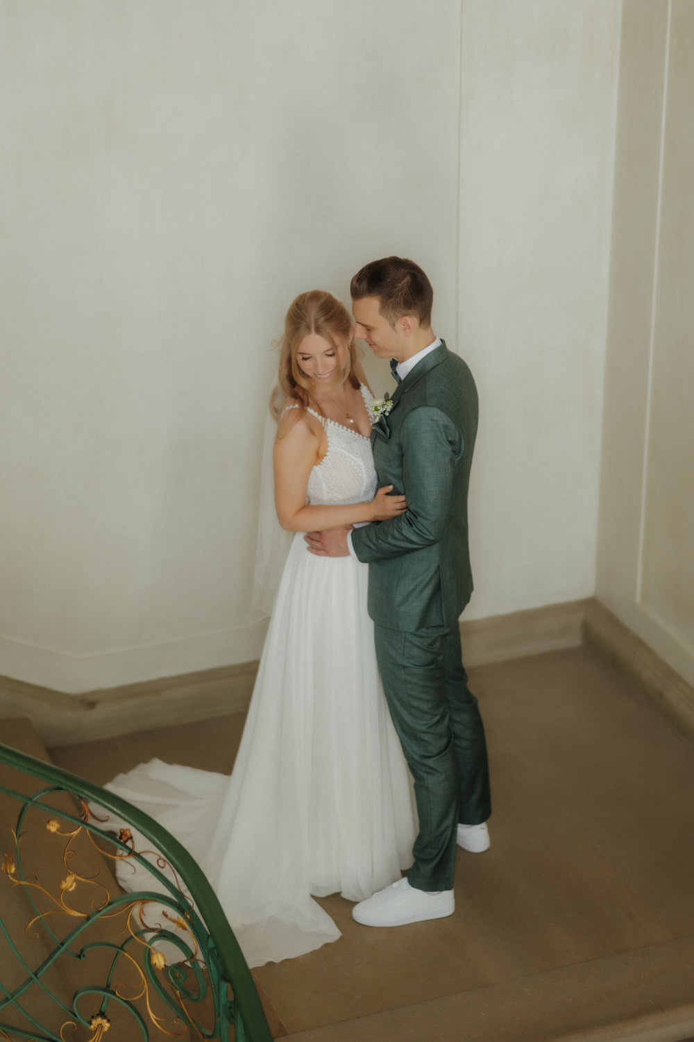 Brautpaar-haelt-sich-in-den-Armen Intimer Moment zwischen Braut und Bräutigam an heller Wand mit Marmorboden