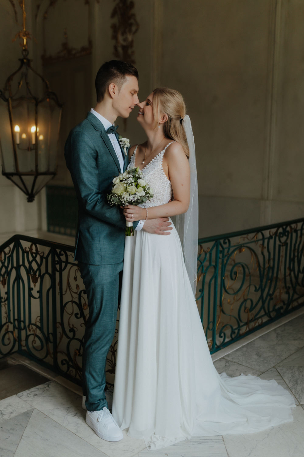 Brautpaar-im-Schloss Braut und Bräutigam schauen sich verliebt an im historischen Treppenhaus