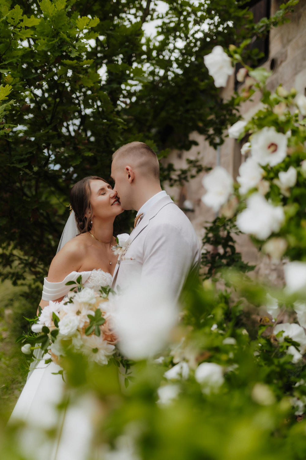 Brautpaar küsst sich im Grünen vor Burgmauer, Heiraten Nörten-Hardenberg