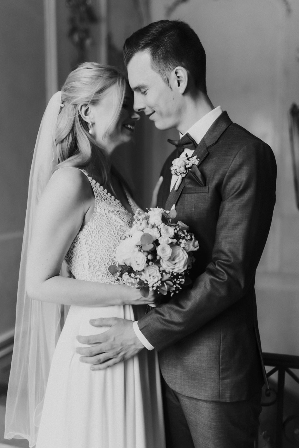 Brautpaar-lachend-beim-Fotoshooting-schwarz-weiss Brautpaar hält sich fest und lächelt, Schwarzweißporträt im Schloss Wilhelmsthal