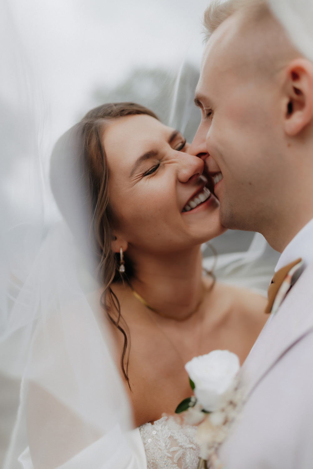 Nahaufnahme mit Schleier, Braut und Bräutigam lachen sich an