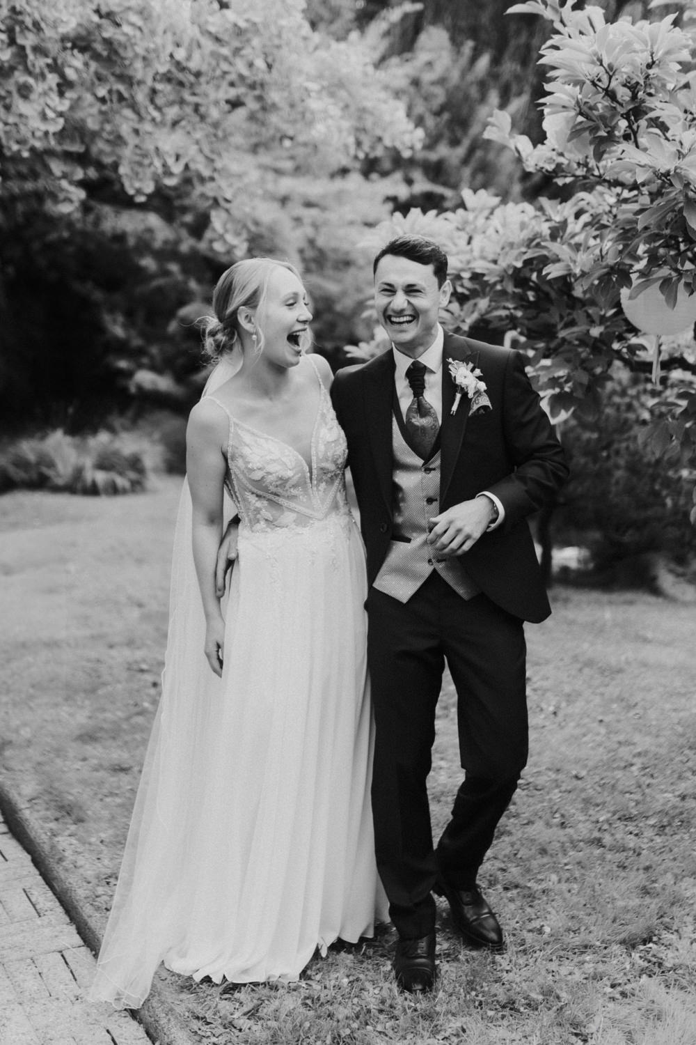Lachendes Brautpaar beim Spaziergang durch einen Garten bei Göttingen