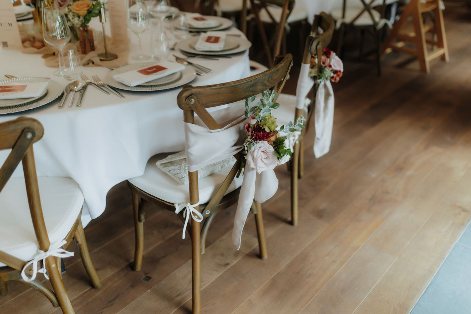 Stühle mit Blumenschmuck bei festlich gedeckter Hochzeitstafel