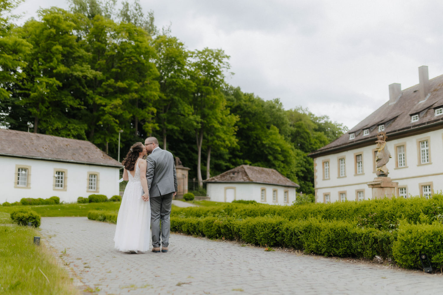 Brautpaar von hinten im Schlossgarten – Hochzeit Schloss Gehrden NRW