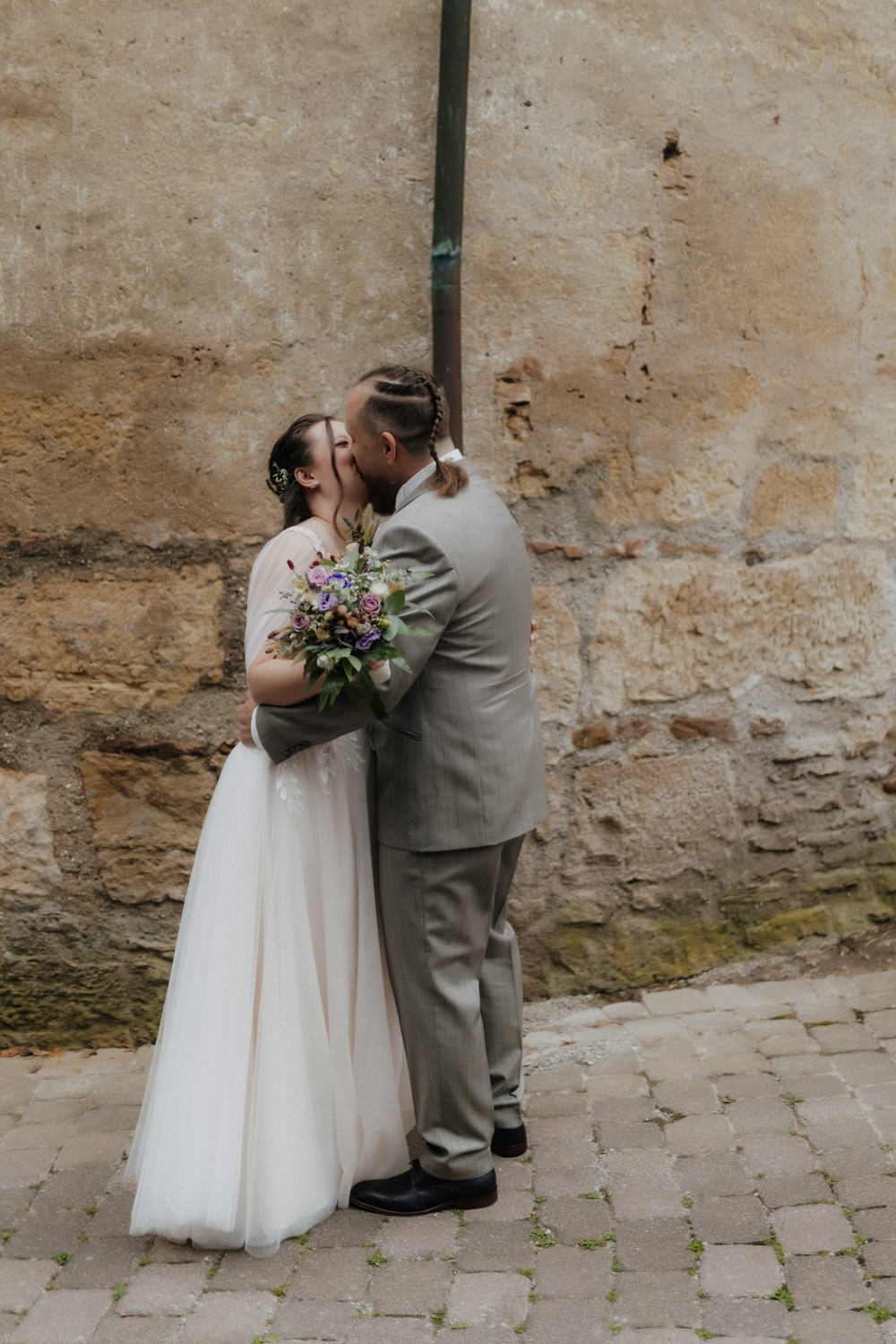 Brautpaar küsst sich vor historischer Steinwand Hochzeit Waldeck