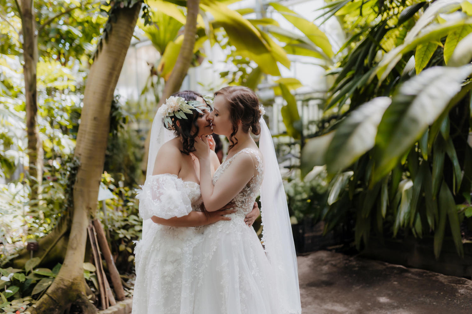 LGBTQ Hochzeit im Botanischen Garten Bonn, zwei Bräute küssen sich zwischen Palmen