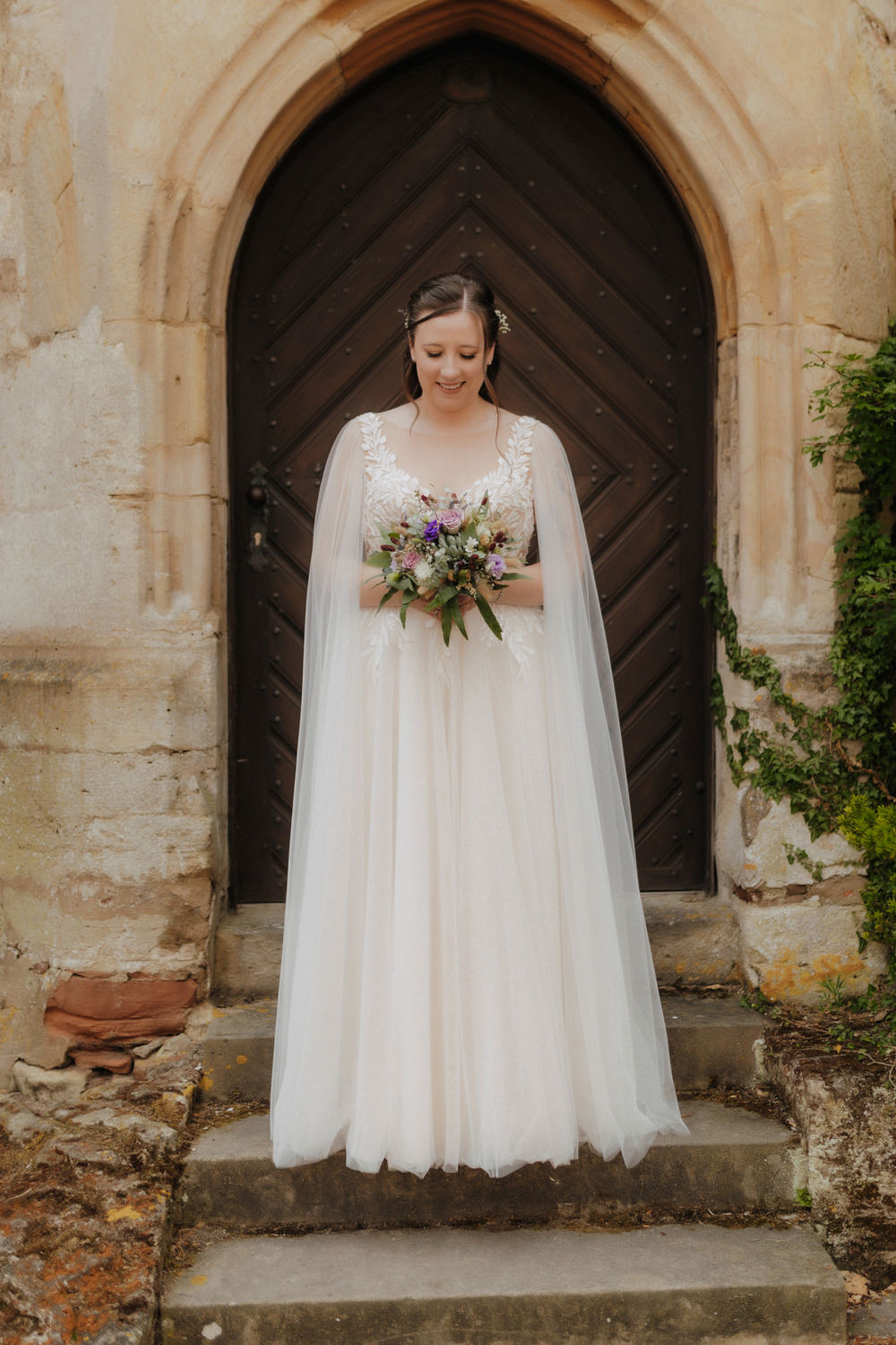 Braut mit Blumenstrauß vor Tür im Schloss Waldeck Hochzeit