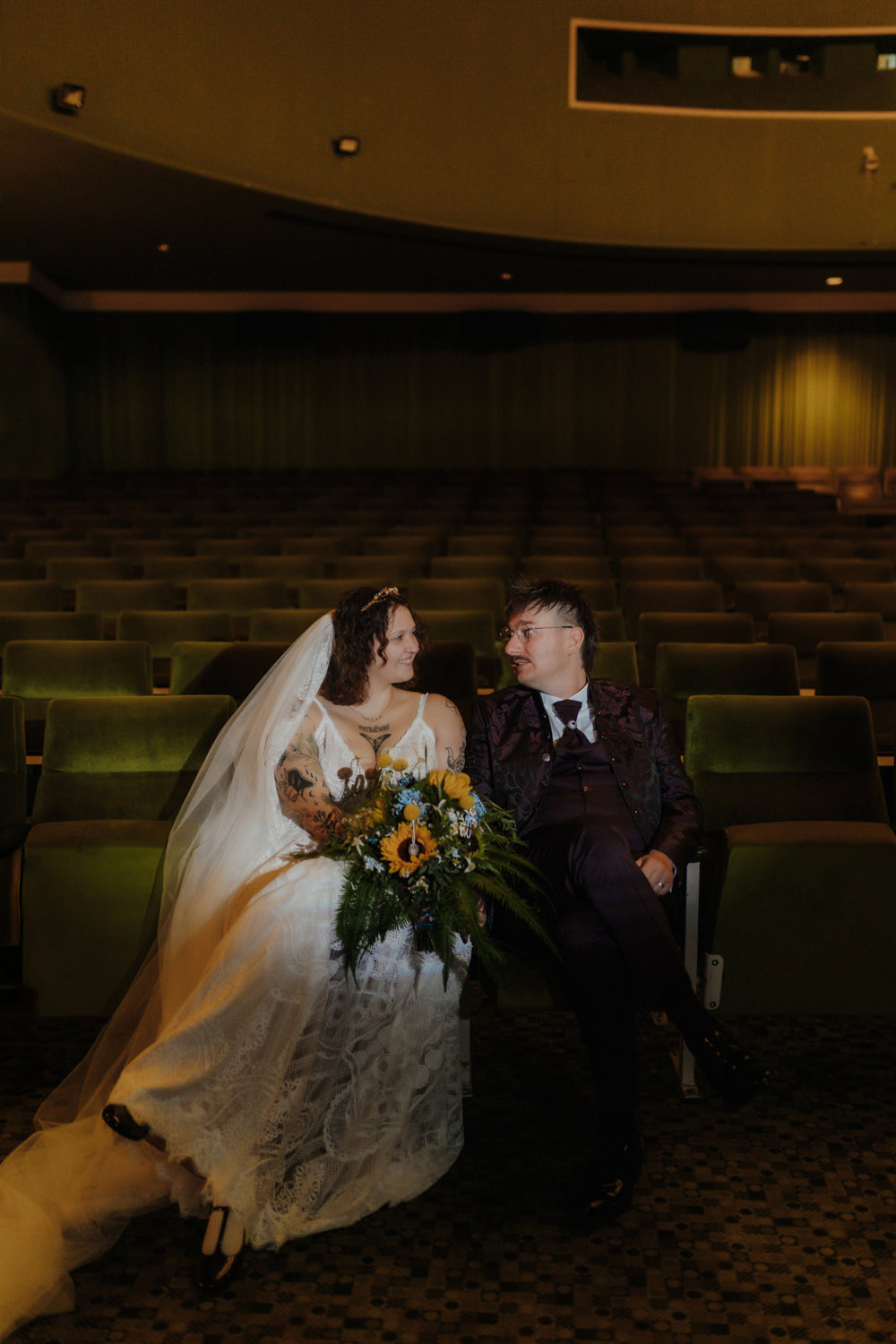 Brautpaar sitzt im Kino Kassel mit Blumenstrauß – natürliche Hochzeitsreportage