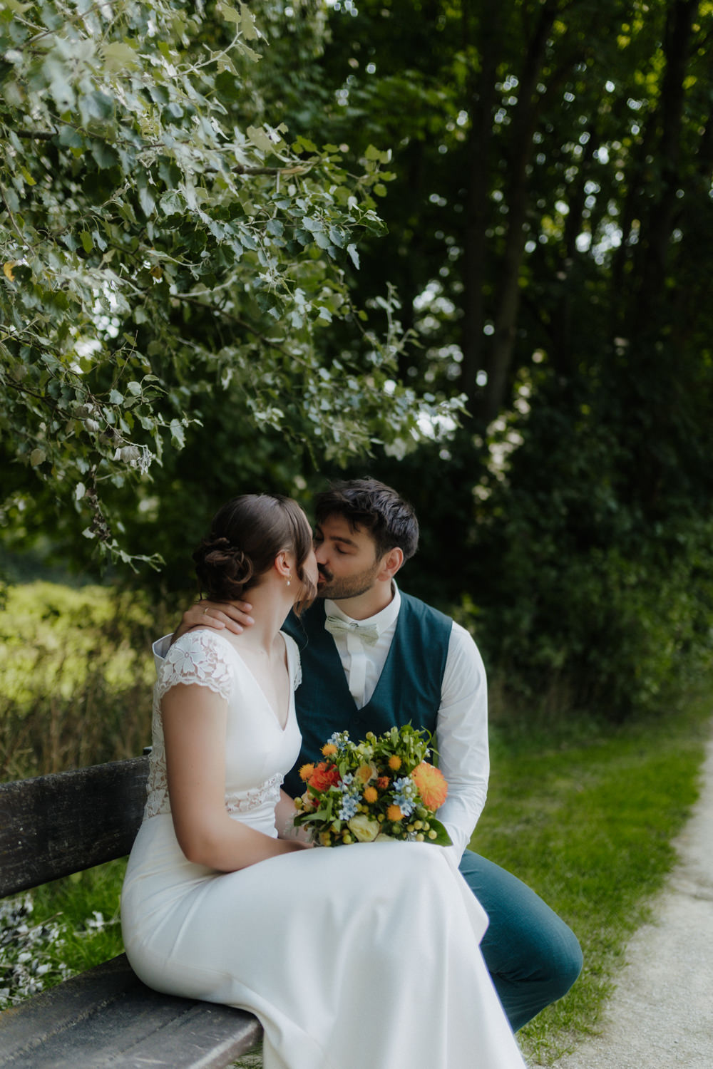 Brautpaar küsst sich auf Bank im Grünen am Kiessee Göttingen Hochzeit