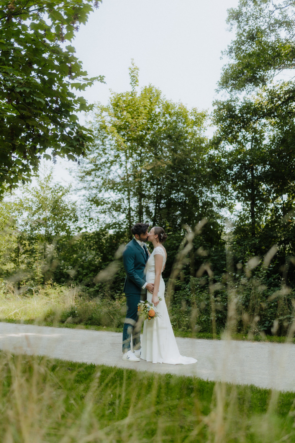 Brautpaar küsst sich auf Weg im Grünen am Kiessee Göttingen Hochzeit