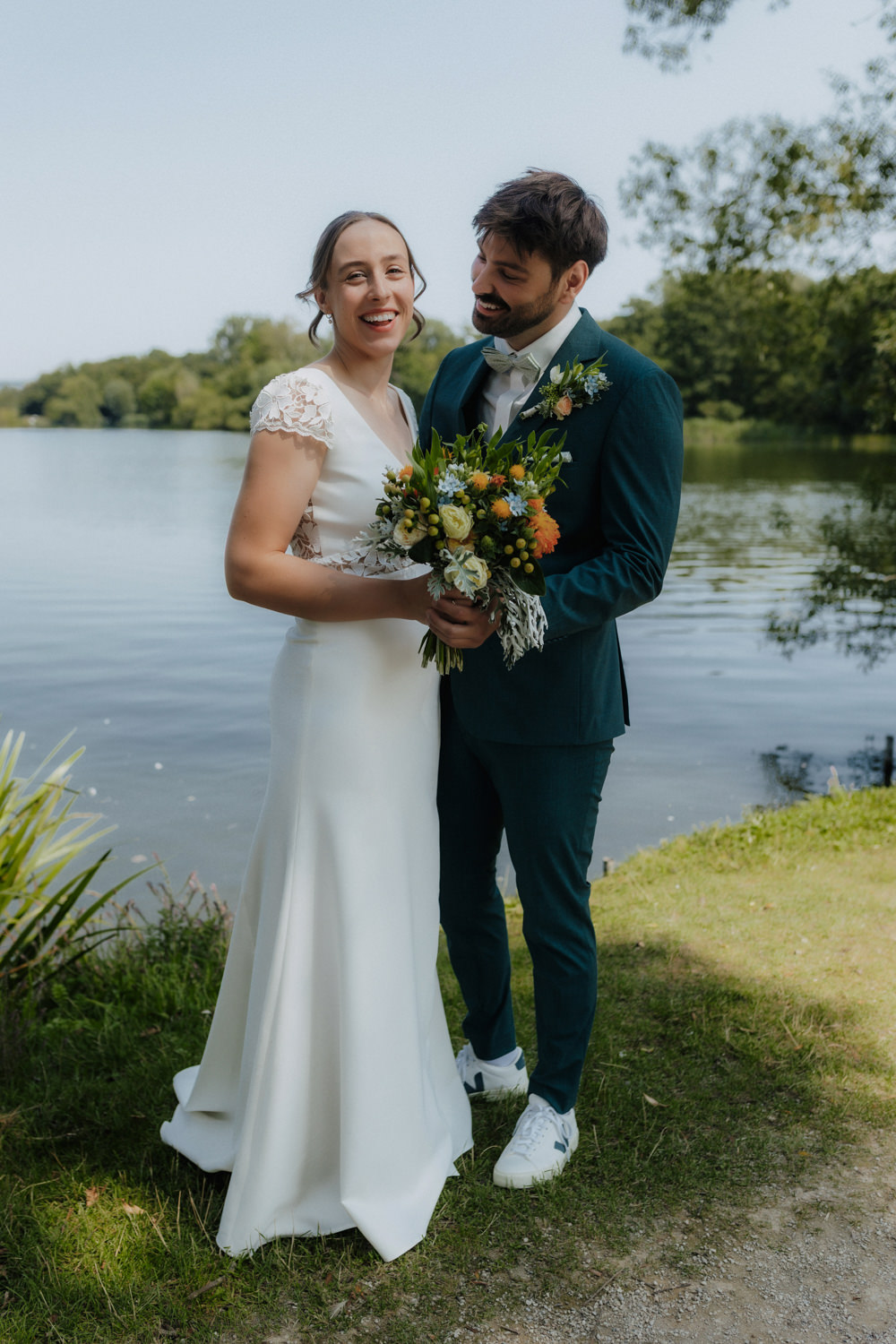 Glückliches Brautpaar mit Blumenstrauß am Kiessee Göttingen Kredo