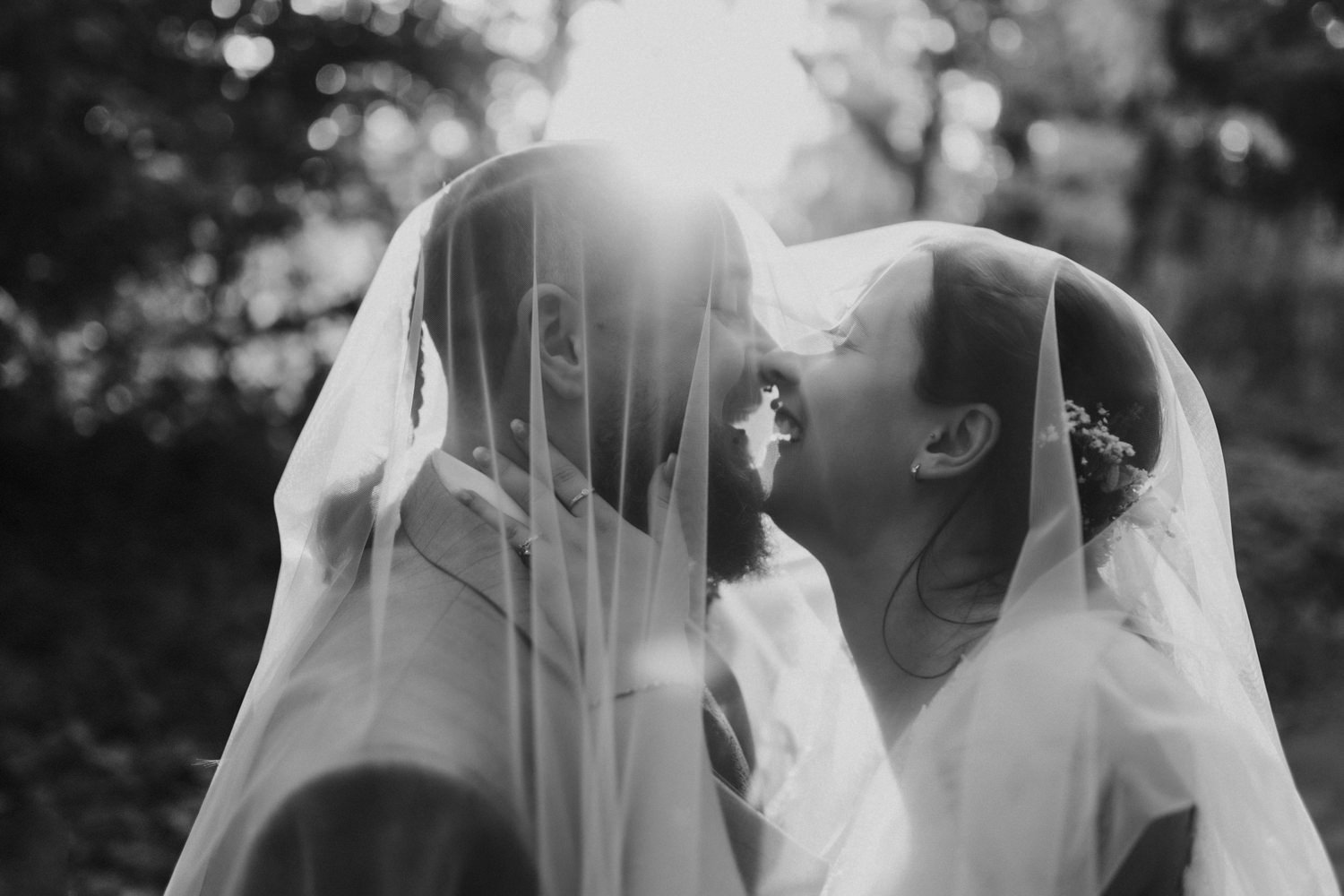 Brautpaar küsst sich unter Schleier romantische Hochzeit im Wald