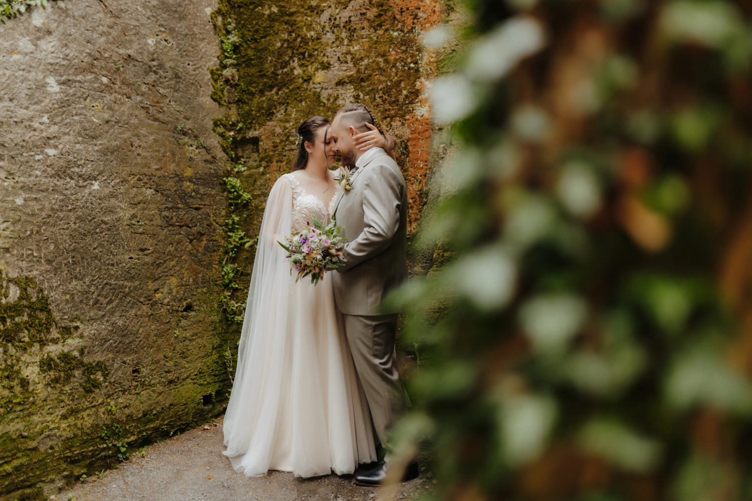 Brautpaar innig umarmt vor alter Steinmauer Schloss Waldeck