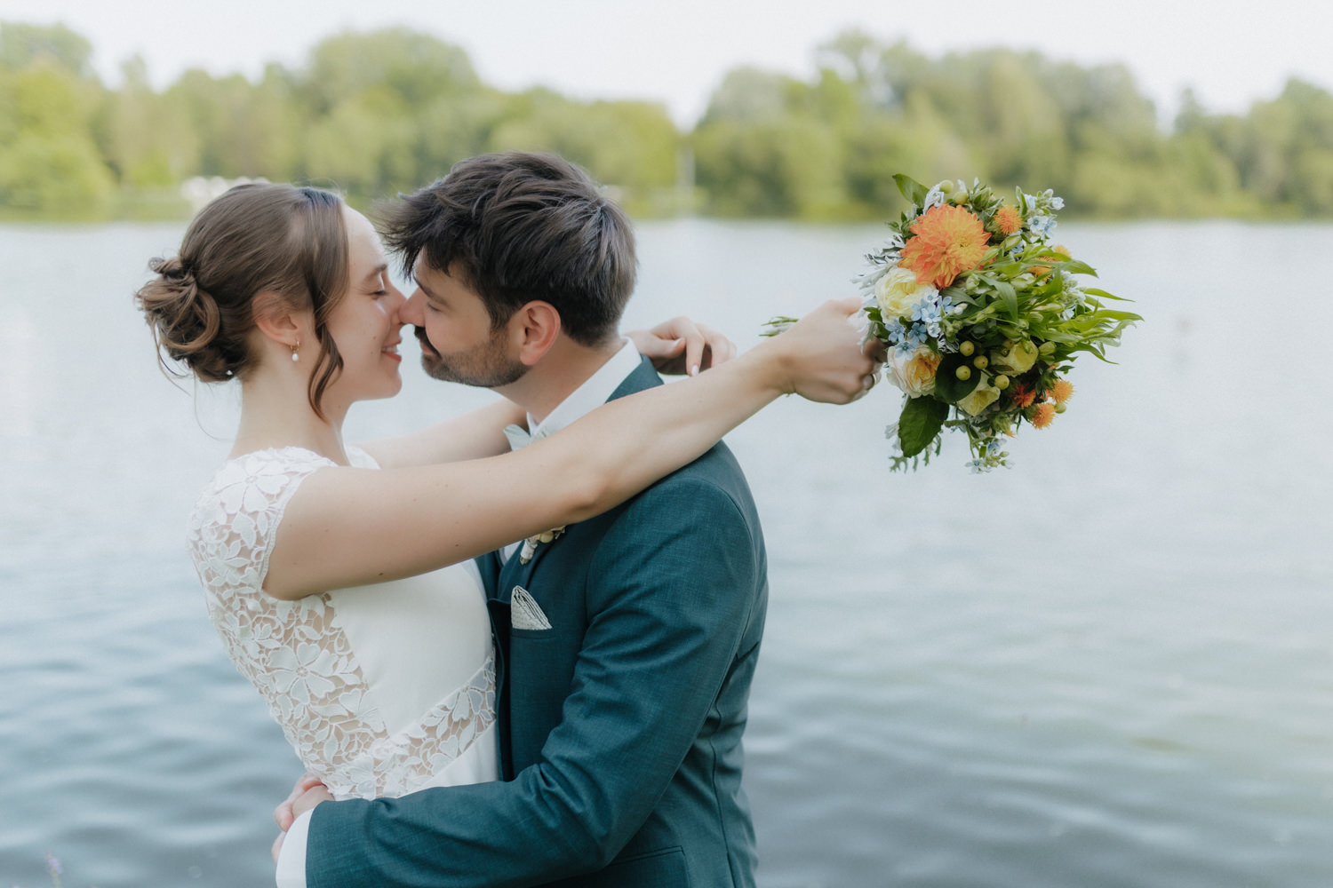 Brautpaar küsst sich mit Blumenstrauß am Kiessee Göttingen Hochzeit