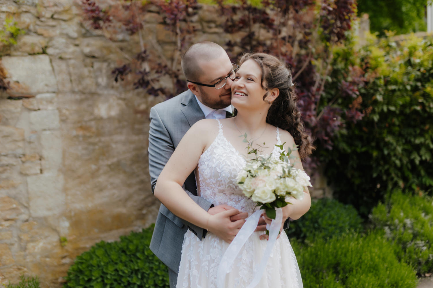 Brautpaar im Garten vor Steinmauer – Hochzeitsbilder Schloss Gehrden