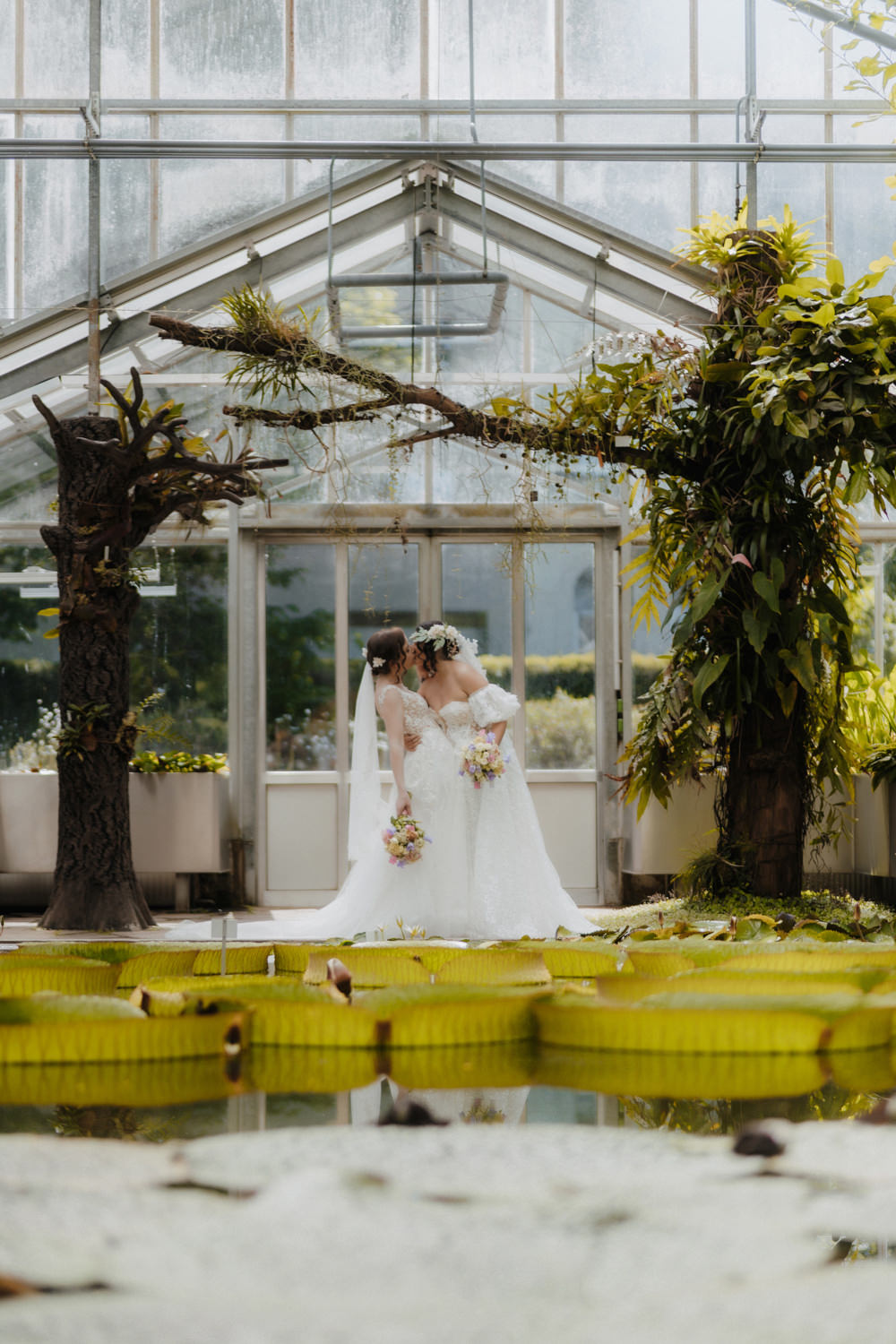 Gleichgeschlechtliche Hochzeit Bonn im Gewächshaus mit Brautpaar am Seerosenteich