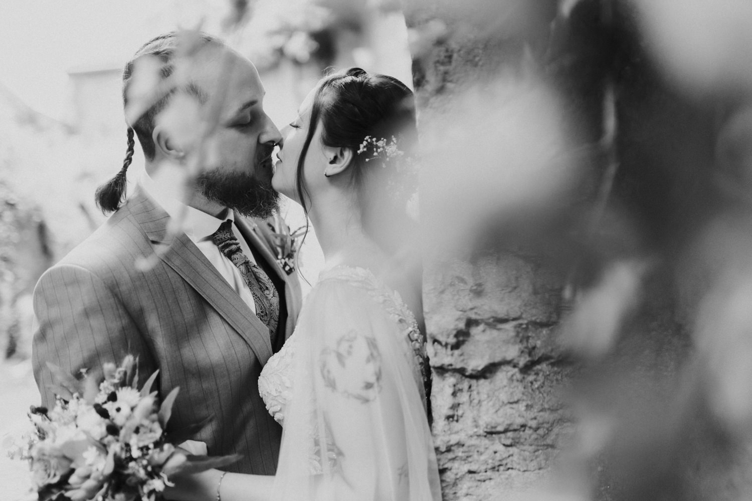 Schwarzweiß Hochzeitsfoto Brautpaar küsst sich im Grünen