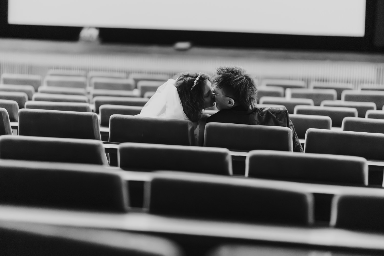 Hochzeit im Kino Kassel – Brautpaar küsst sich zwischen leeren Sitzen