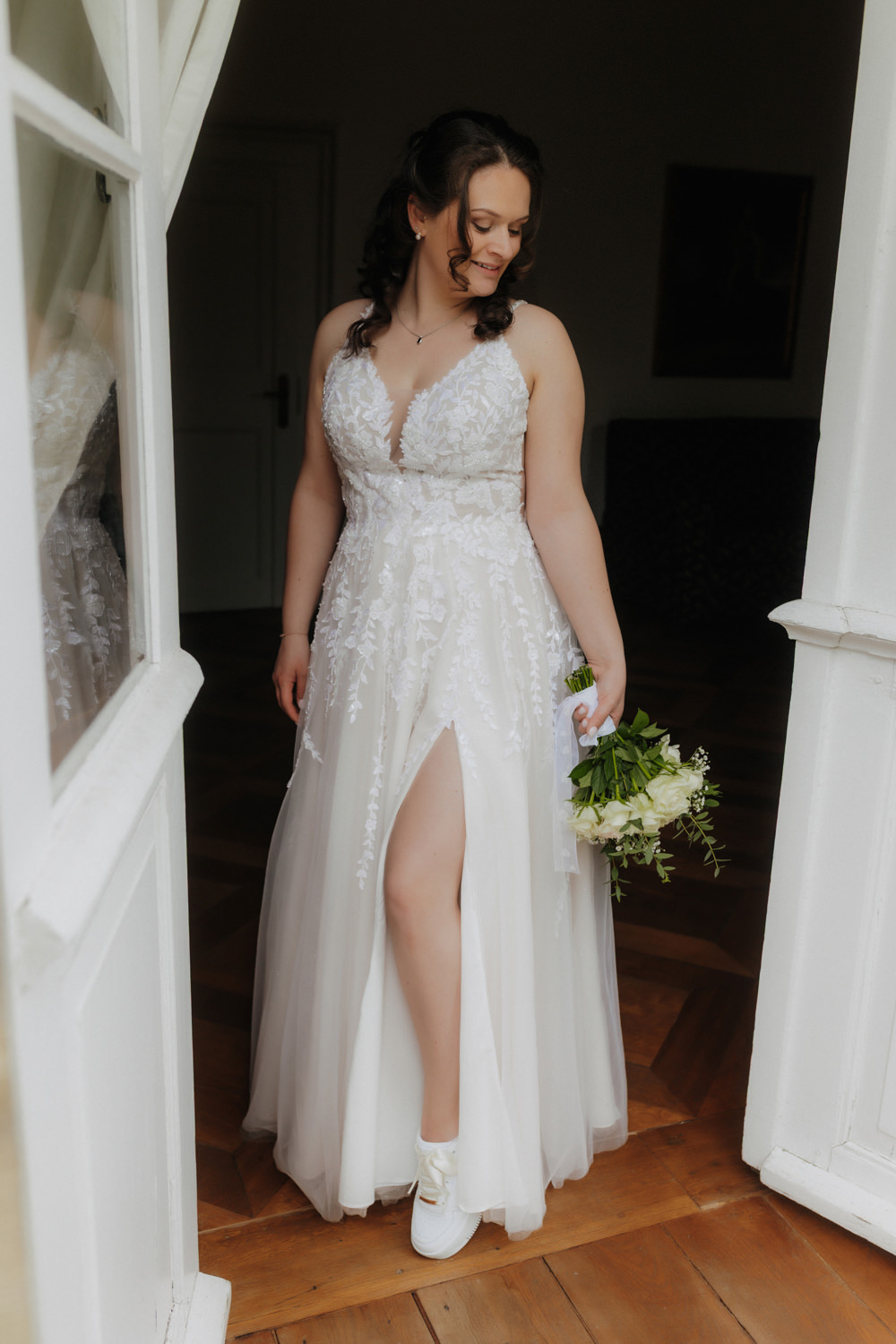 Braut zeigt Brautschuhe im Kleid – moderne Hochzeitsfotografie Paderborn