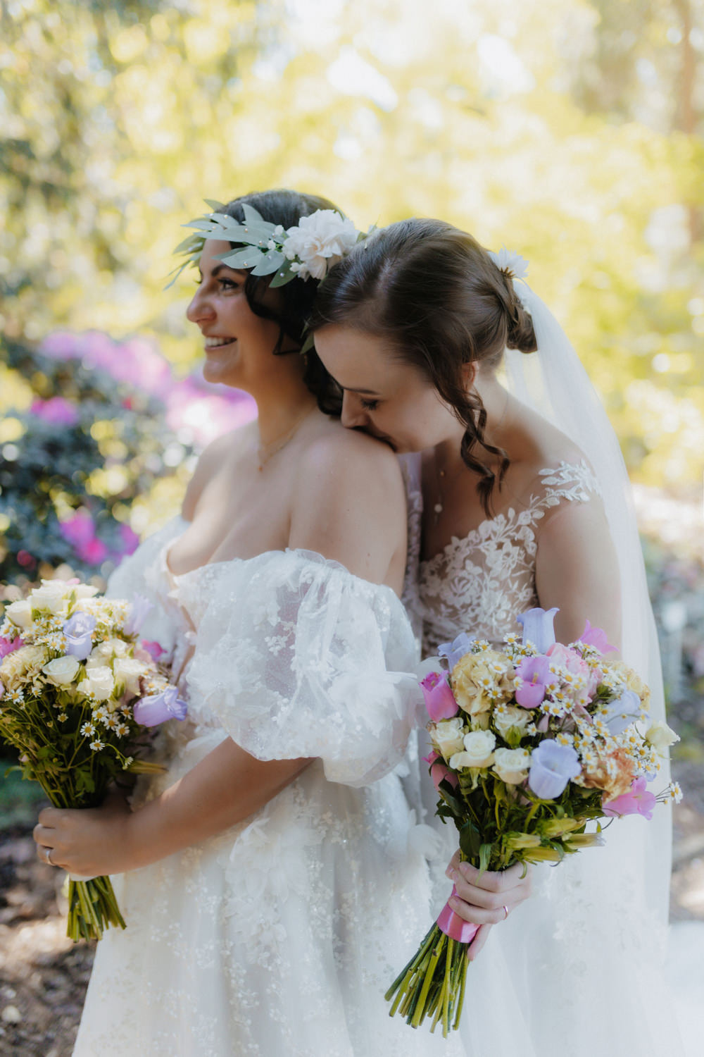 Emotionale Umarmung zweier Bräute mit buntem Brautstrauß