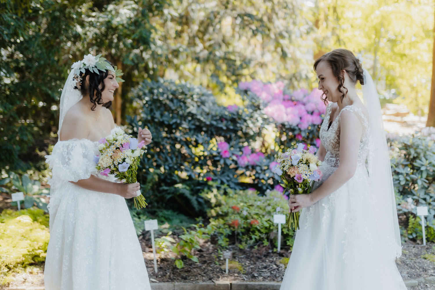 Zwei Bräute lachen gemeinsam bei romantischer Hochzeit im Grünen