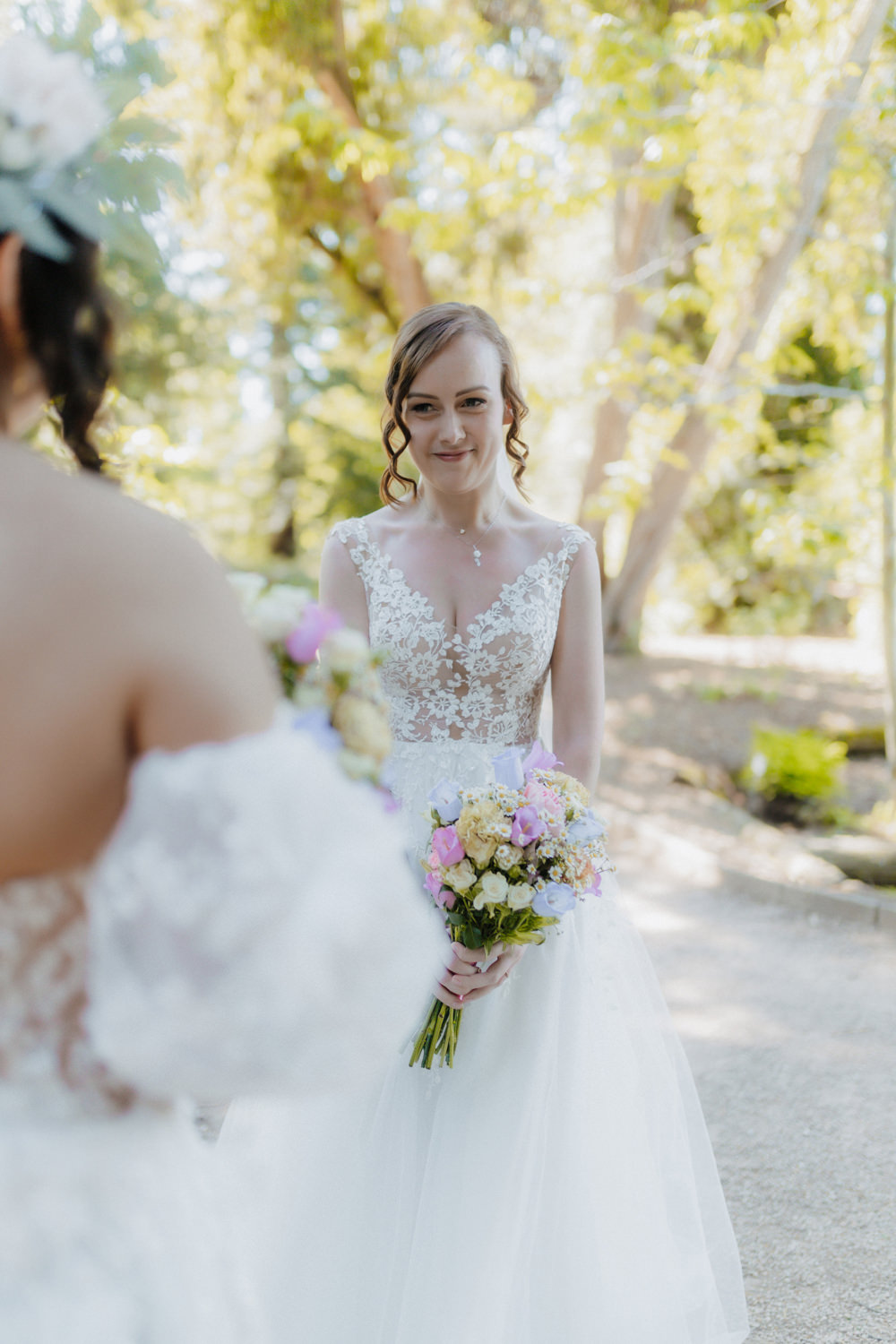 Braut blickt verliebt zur Partnerin, freie Trauung im Grünen