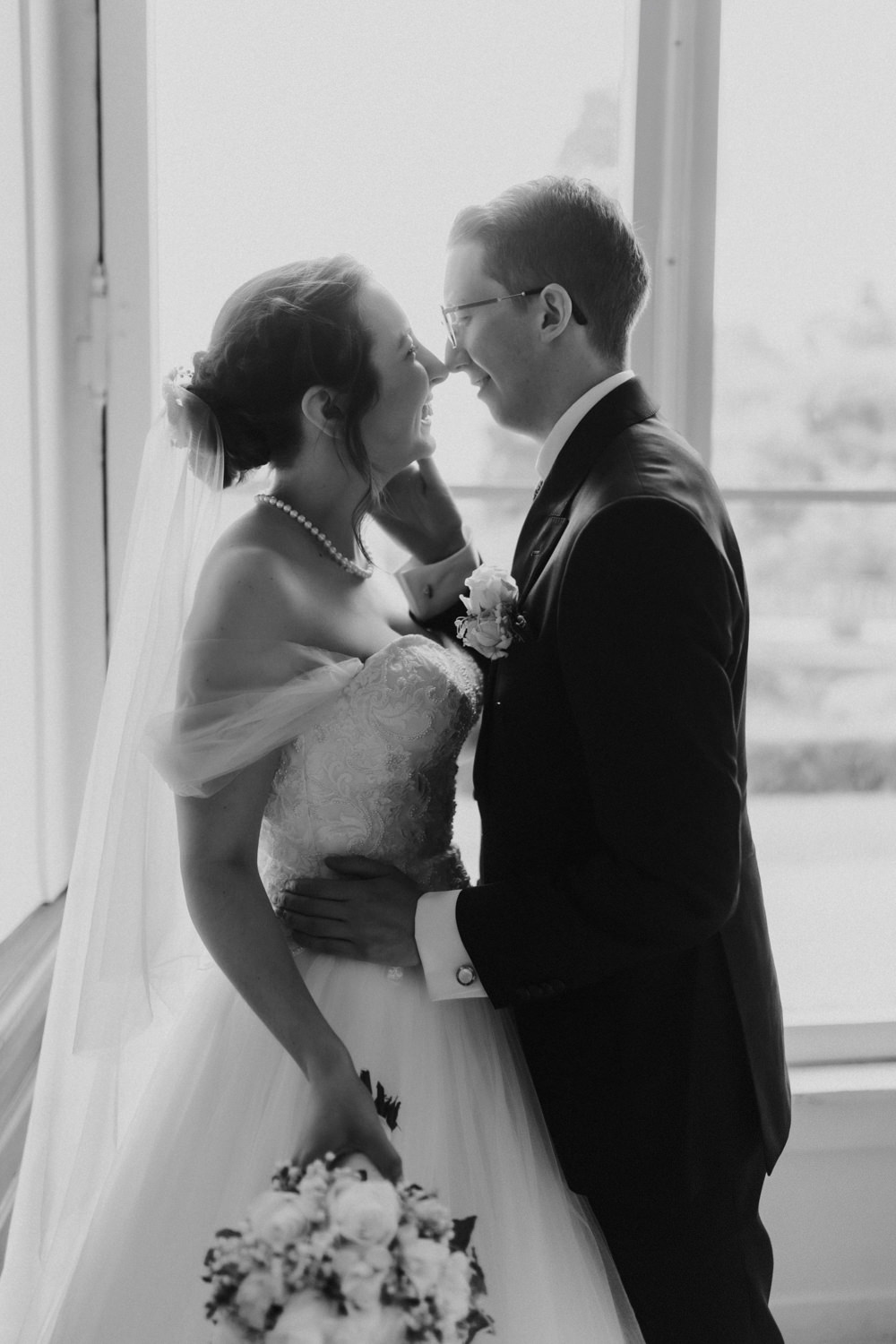 Schwarzweiß Brautpaar Portrait am Fenster romantische Hochzeitsfotografie