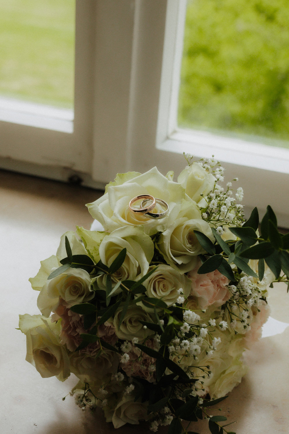 Eheringe auf Brautstrauß am Fenster – Hochzeitsfotograf Paderborn