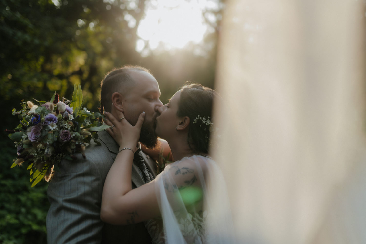 Romantischer Kuss Brautpaar im Sonnenlicht Hochzeitsfotograf Waldeck