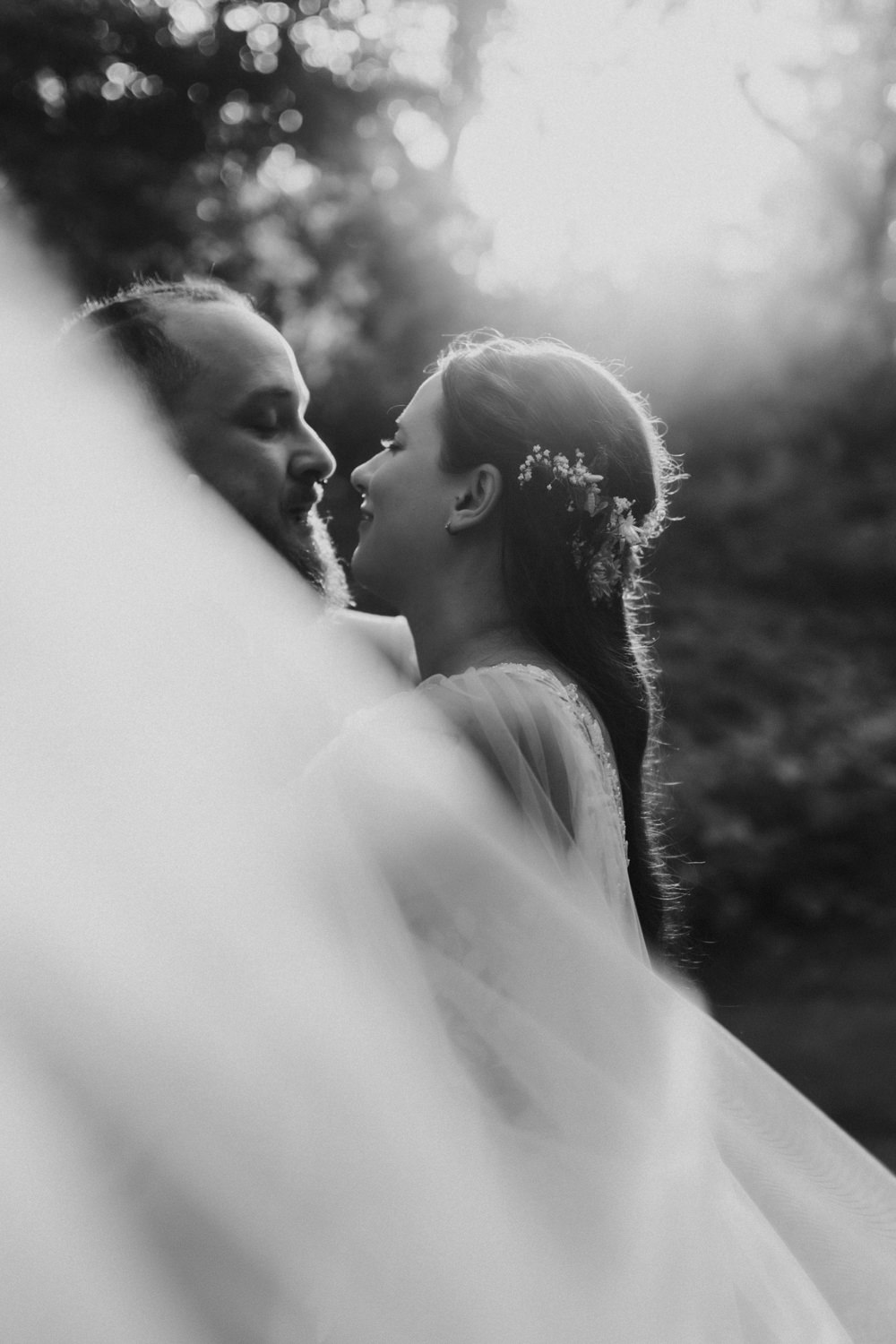 Schwarzweiß Hochzeitsfoto Brautpaar mit Schleier im Gegenlicht