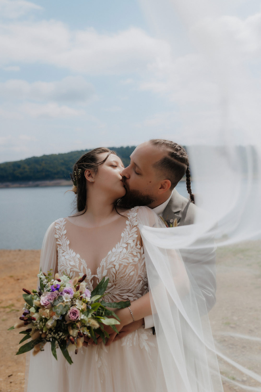 Brautpaar küsst sich am Edersee mit Schleier Hochzeitsfoto